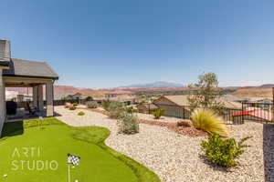 Fenced backyard with a patio area, a putting area, a mountain view, and a residential view