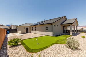 Rear view of house with an area to practice putting, a patio, a fenced backyard, and stucco siding