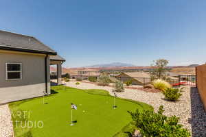 Fenced backyard featuring a putting green and a mountain view