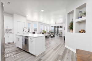 Kitchen with stainless steel appliances, light wood finished floors, white cabinetry, a kitchen island with sink, and recessed lighting