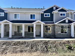 Craftsman-style home with stone siding, board and batten siding, a porch, and roof with shingles