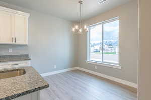 Unfurnished dining area featuring light wood finished floors and a chandelier