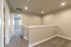 Hallway featuring dark carpet, recessed lighting, and an upstairs landing