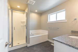 Bathroom with a bath, a stall shower, vanity, and recessed lighting