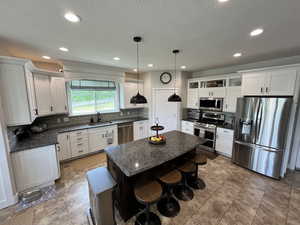 Kitchen with appliances with stainless steel finishes, tasteful backsplash, white cabinets, a kitchen bar, and a textured ceiling