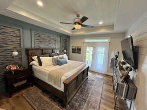 Bedroom featuring a raised ceiling, access to outside, wood finished floors, recessed lighting, and ceiling fan