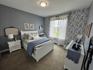 Bedroom with dark carpet and a textured ceiling