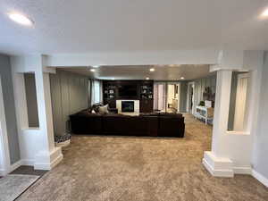 Carpeted living area with a glass covered fireplace, a textured ceiling, and recessed lighting