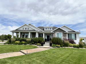 Craftsman house with a front lawn, stone siding, and roof with shingles