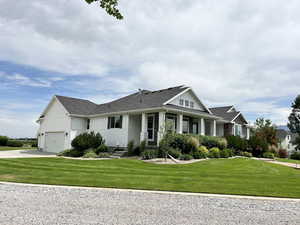 View of front facade featuring board and batten siding, driveway, a front yard, and an attached garage
