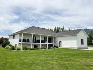 Back of house featuring a lawn and roof with shingles