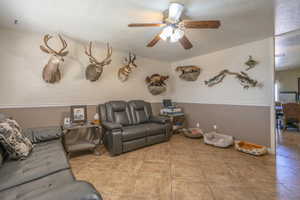 Tiled living area featuring ceiling fan and a textured ceiling