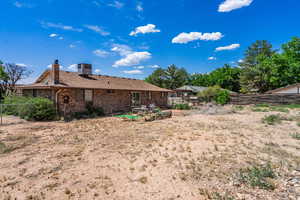 Rear view of house featuring a chimney, a fenced backyard, and brick siding