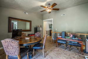 Dining room featuring ceiling fan, a textured ceiling, light tile patterned flooring, and an office area