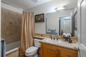 Bathroom featuring vanity, tiled shower / bath combo, and a textured ceiling