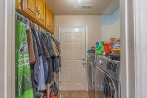 Washroom featuring independent washer and dryer, light tile patterned flooring, and a textured ceiling