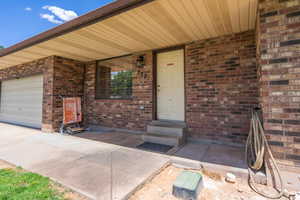 Doorway to property featuring brick siding and a garage