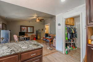 Kitchen featuring freestanding refrigerator, a ceiling fan, a textured ceiling, vaulted ceiling, and light wood finished floors