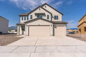 Modern farmhouse with concrete driveway, board and batten siding, a garage, roof with shingles, and a mountain view