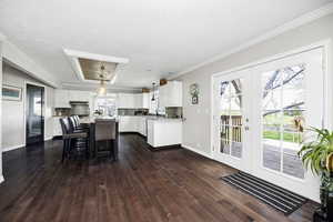Kitchen featuring white cabinetry, decorative backsplash, a kitchen island, dark wood finished floors, and ornamental molding