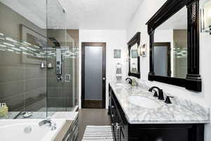 Master Bathroom featuring a shower stall, double vanity, a garden tub, a textured ceiling, and wood finished floors