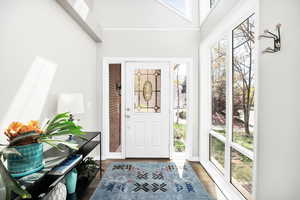 Foyer with wood finished floors and a towering ceiling