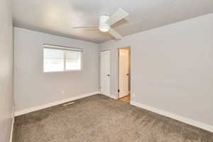 Carpeted empty room featuring ceiling fan and baseboards