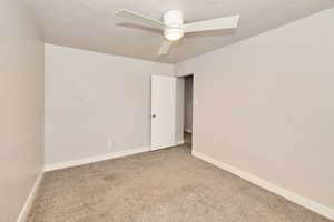 Carpeted spare room with ceiling fan and baseboards