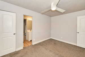 Unfurnished bedroom with carpet, ensuite bathroom, tile patterned floors, and a ceiling fan