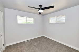 Spare room with plenty of natural light, carpet, and a ceiling fan