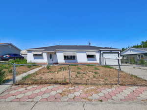 Single story home with brick siding, concrete driveway, a fenced front yard, and an attached garage