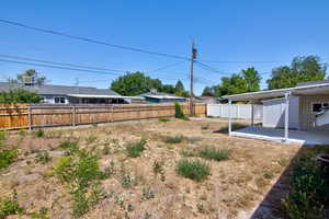 Fenced backyard featuring a carport and a patio