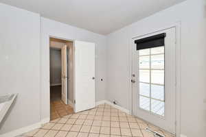 Doorway with baseboards and light tile patterned floors