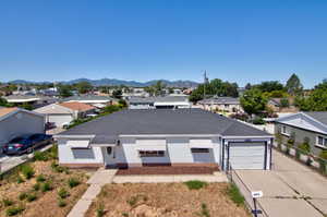 View of front facade featuring concrete driveway, a garage, a residential view, and a mountain view