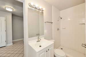Bathroom featuring tiled shower, vanity, and tile patterned flooring