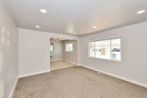 Spare room featuring light colored carpet, recessed lighting, arched walkways, and a chandelier