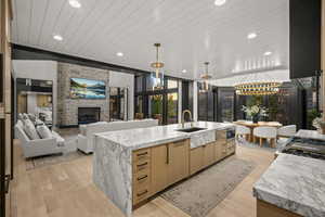 Kitchen featuring wooden ceiling, a stone fireplace, light brown cabinetry, recessed lighting, and light stone countertops