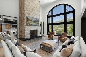 Living room with a towering ceiling, wood finished floors, a stone fireplace, healthy amount of natural light, and recessed lighting