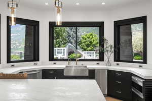 Kitchen with stainless steel appliances, dark cabinetry, recessed lighting, light stone counters, and pendant lighting