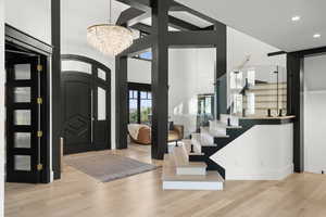 Entrance foyer with a chandelier, wood finished floors, stairs, recessed lighting, and a towering ceiling