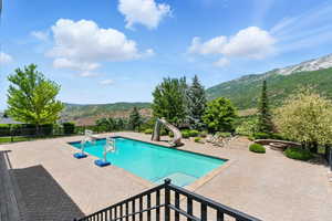 View of swimming pool featuring a water slide, a mountain view, and a patio area