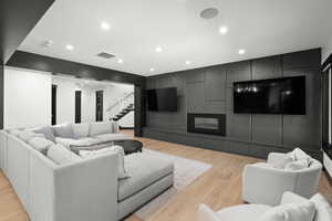 Living area featuring stairway, light wood-type flooring, recessed lighting, and a glass covered fireplace