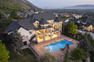 Rear view of property with a balcony, a standing seam roof, a fenced backyard, and a mountain view