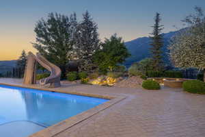 View of pool with a mountain view, a water slide, and a patio