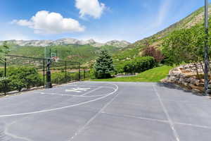 View of sport court featuring a mountain view, community basketball court, and a yard