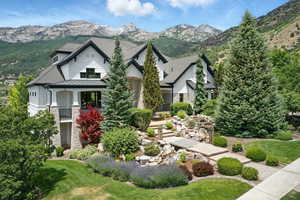 Craftsman-style house with a standing seam roof, stone siding, a mountain view, a metal roof, and a front lawn