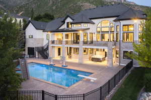 Rear view of property with a patio, a fenced backyard, stairs, a mountain view, and a balcony