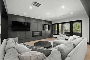 Living area with recessed lighting, light wood-type flooring, and a glass covered fireplace
