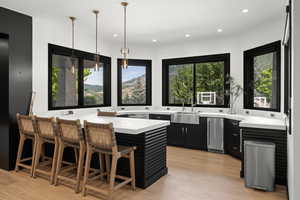 Kitchen featuring dark cabinets, light countertops, a breakfast bar, light wood finished floors, and a peninsula