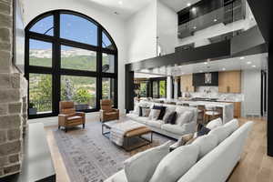 Living area featuring light wood-style floors, recessed lighting, plenty of natural light, and a towering ceiling